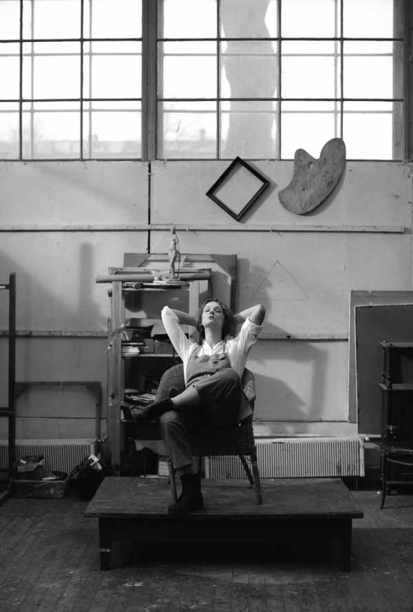 grayscale photo of a woman resting on a wooden chair